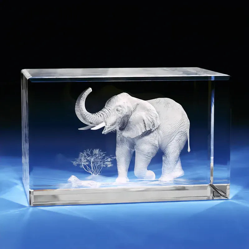 Rectangular crystal block showcasing a 3D engraved elephant with raised trunk and savannah scenery, placed on a glowing blue b