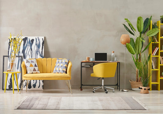 Modern home office with a yellow chair, cozy loveseat, indoor plants, and artistic decor, creating a calming and organized spa