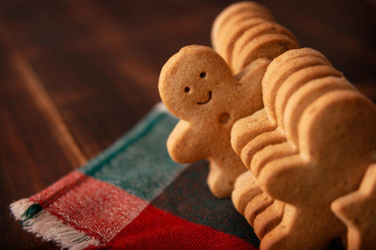 Row of gingerbread man cookies lined up on a festive cloth with a smiling cookie in focus.