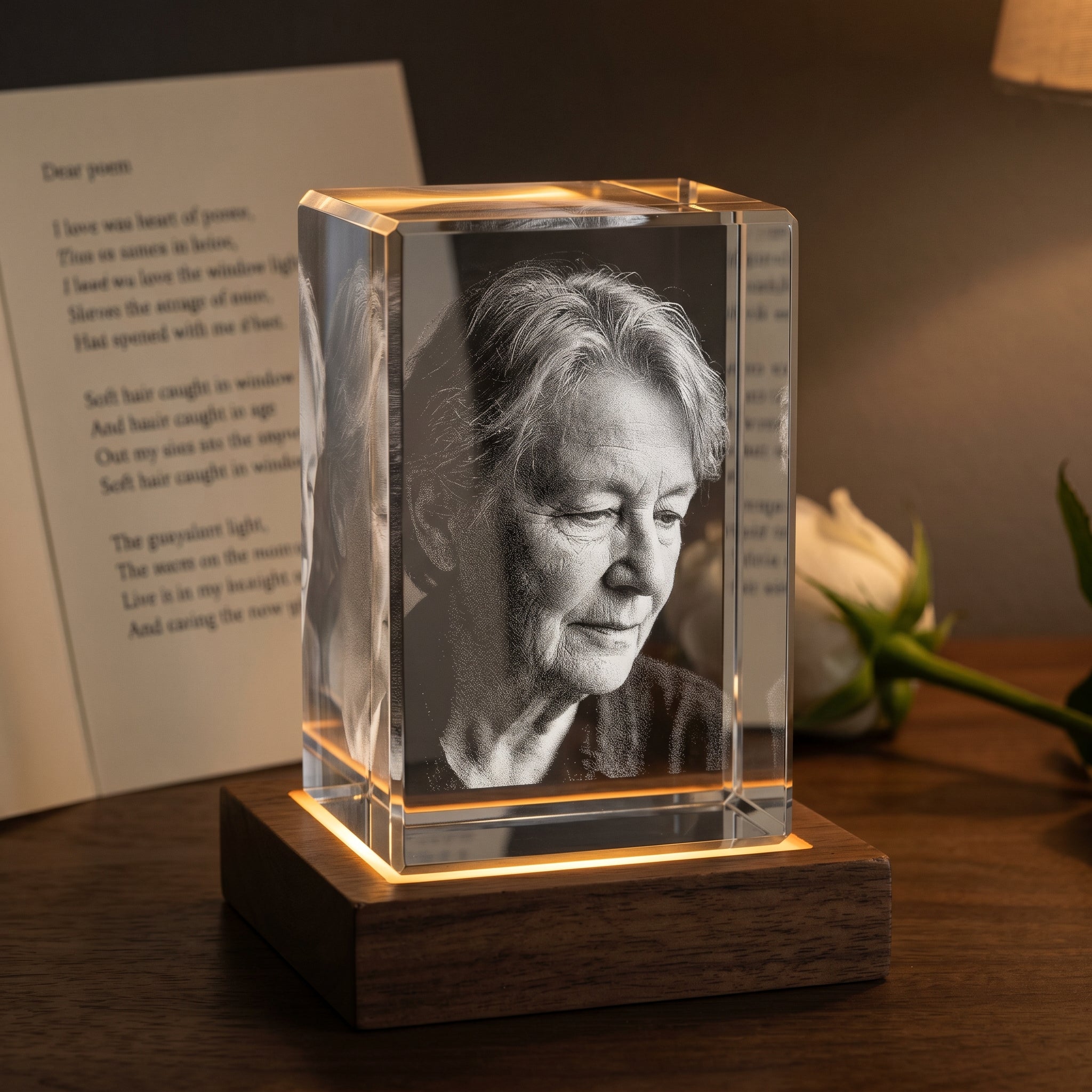 Walnut rectangle 3D Crystal with engraved candid older person profile in pure grayscale, dim mantle with handwritten poem cardstock and single white rose